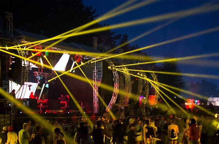 Gelbe Lichtstrahlen über einer Open-Air-Bühne bei Nacht